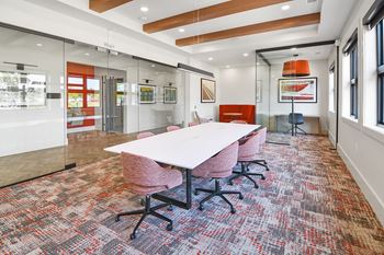 a conference room with a long white table and pink chairs